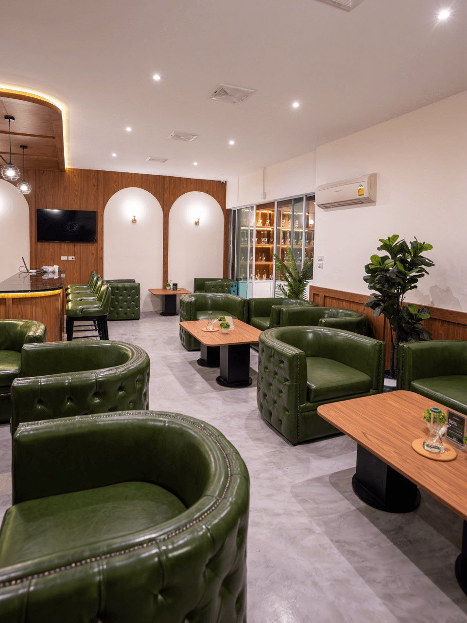 Lounge with green armchairs and tables inside CannaBuri, Pattaya