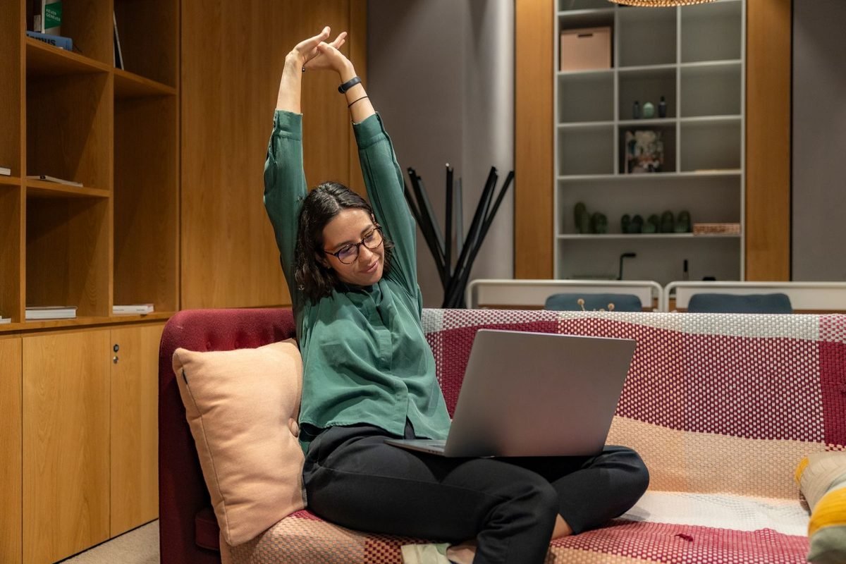 Woman stretching while working on her laptop