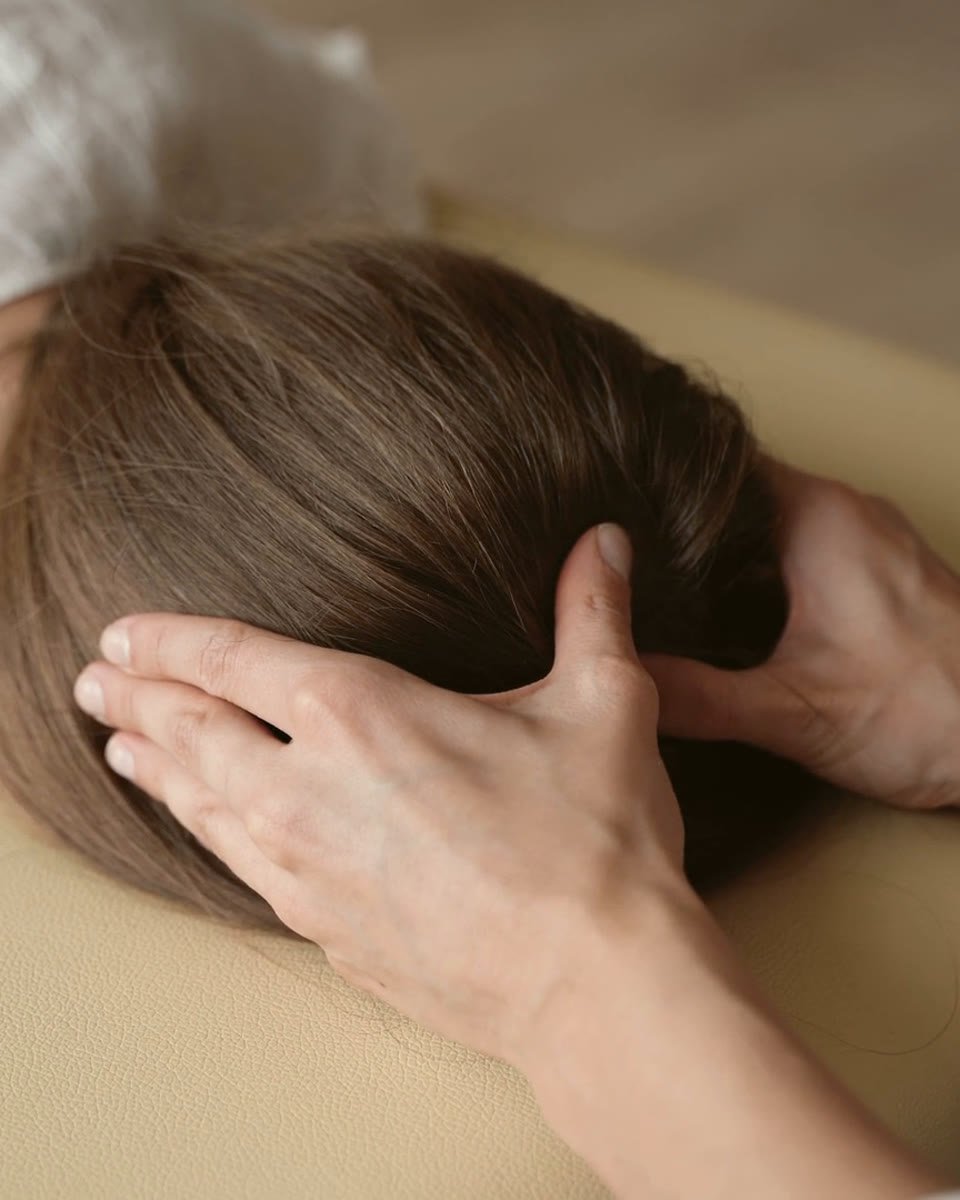 Chiropractor's hands gently supporting a patient's head during a neck release